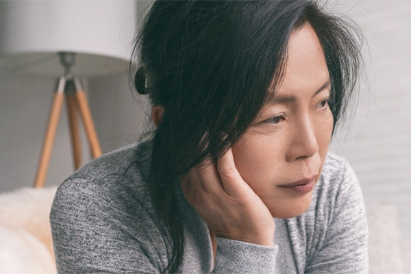 A middle-aged asian woman rests her head on her hand with exhaustion. Get treatment for chronic disease from Morgan Burns, APRN in New Smyrna Beach.
