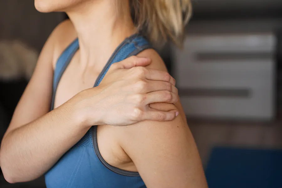A woman massages her sore shoulder. Get chronic inflammation treatment from Morgan Burns, APRN in New Smyrna Beach.