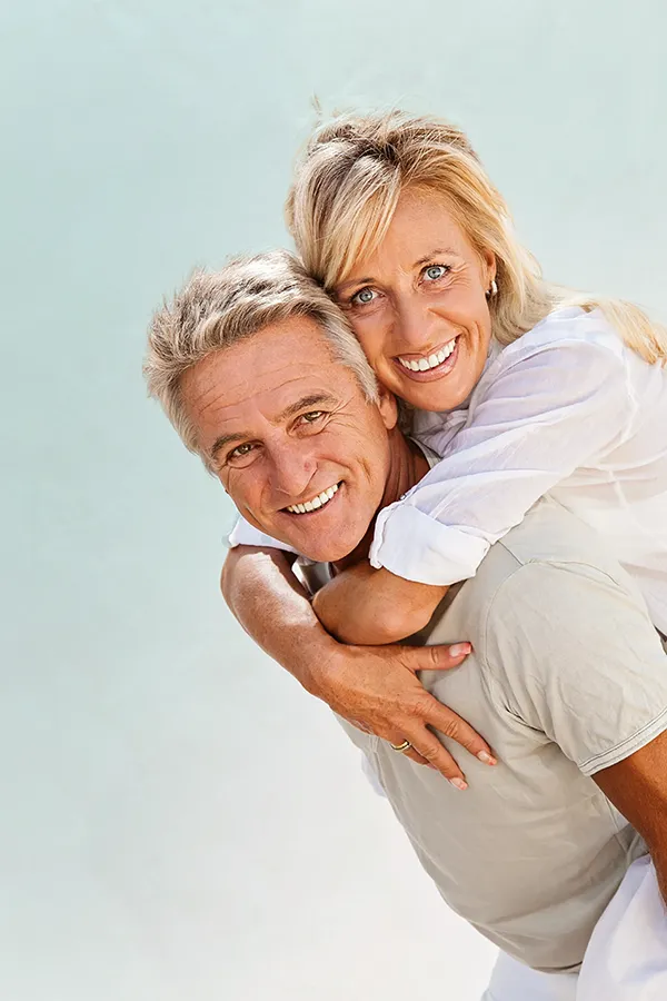 A happy mature couple having fun - the husband is carrying his wife on his back. Get treatment for food allergies from Morgan Burns, APRN in New Smyrna Beach.