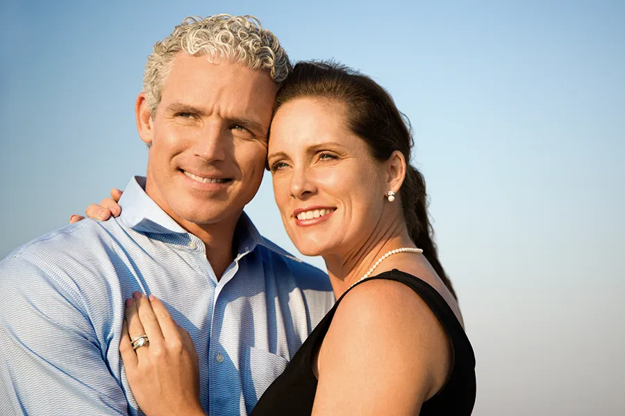 A middle-aged caucasian couple embraces in the sunshine, happy with the healthy aging peptide treatments from Morgan Burns, APRN in New Smyrna Beach