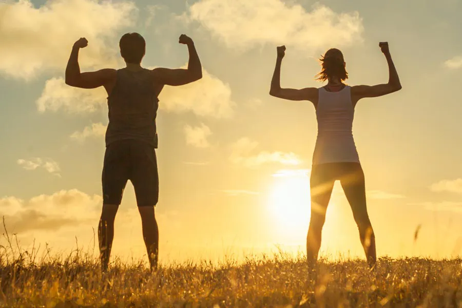 A couple flex their arms outside in the sunrise. Schedule Immune Optimization Peptide Treatment from Morgan Burns, APRN in New Smyrna Beach.