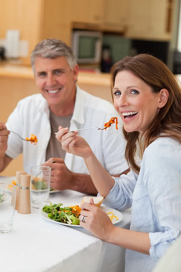 Improve digestion with Morgan Burns, APRN's Functional Medicine for Leaky Gut Syndrome care in New Smyrna Beach, featuring a happy couple enjoying a nutritious lunch at home.
