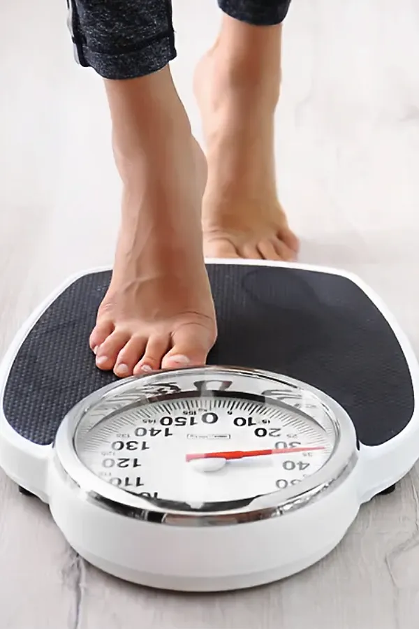 A woman steps onto a scale. Get Metabolilc and Weight Optimization Peptides treatment from Morgan Burns, APRN in New Smyrna Beach.