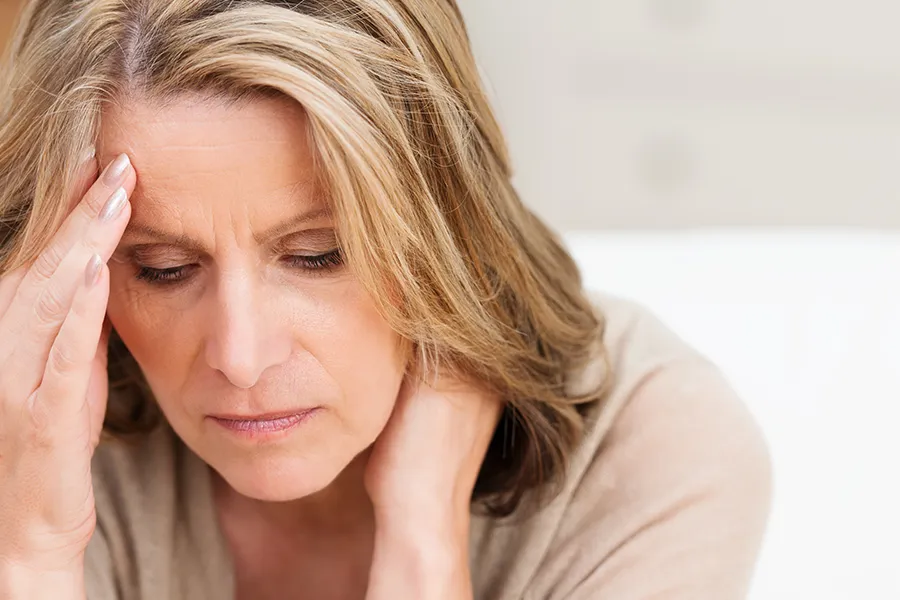 A woman rubs her forehead with worry. Schedule treatment for mood imbalances from Morgan Burns, APRN in New Smyrna Beach.