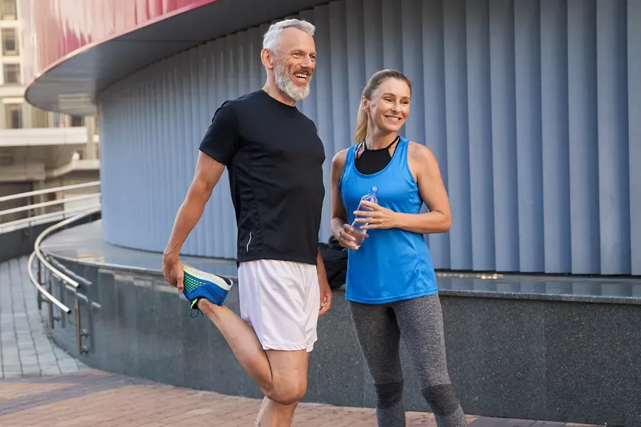 A middle-aged couple happily stretch and prepare for exercise after receiving effective peptide therapy for healing and recovery from Morgan Burns, APRN in New Smyrna Beach.