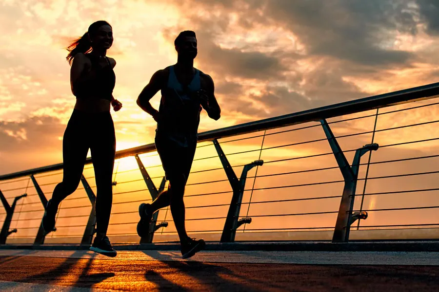 A couple jogging on a bridge at sunrise, representing performance enhancing peptide therapy from Morgan Burns, APRN in New Smyrna Beach.
