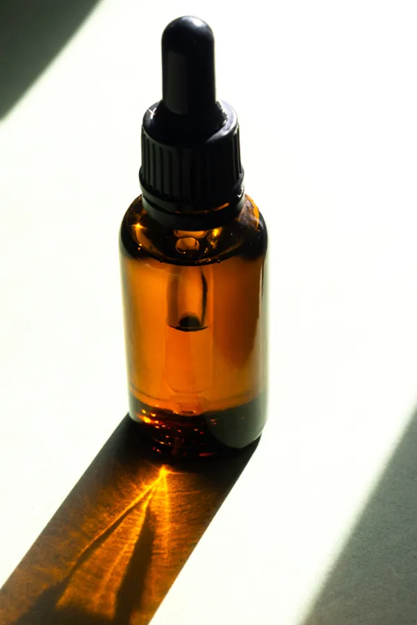 A brown dropper bottle on a table lit by sunlight, representing performance enhancing peptide treatment from Morgan Burns, APRN in New Smyrna Beach.
