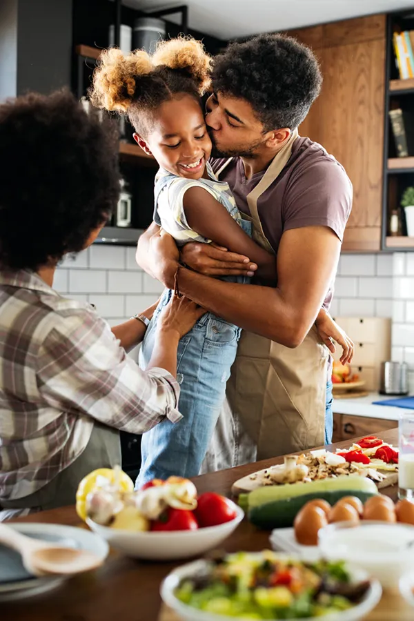 A black family happily makes a healthy meal. Get treatment for pre-diabetes from Morgan Burns, APRN in New Smyrna Beach.