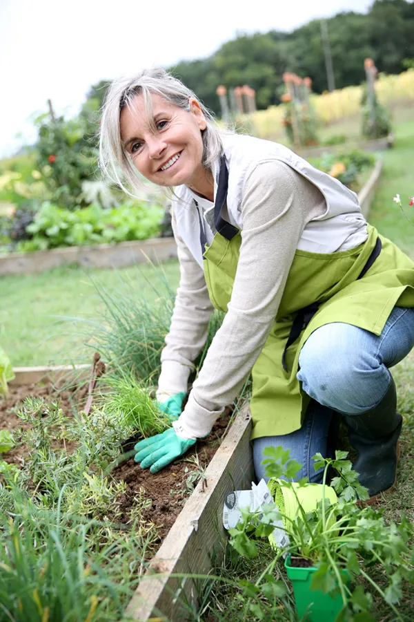 A mature woman bending down working on her garden happily after successful rheumatoid arthritis treatment from Morgan Burns, APRN in New Smyrna Beach.