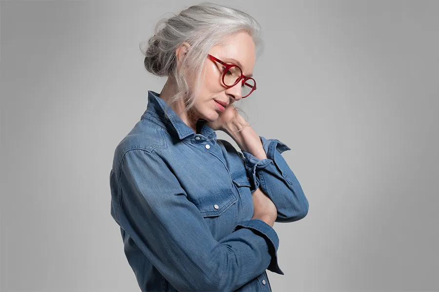 A middle-aged woman rubs her neck from stress. Schedule treatment for stress and burnout from Morgan Burns, APRN in New Smyrna Beach.