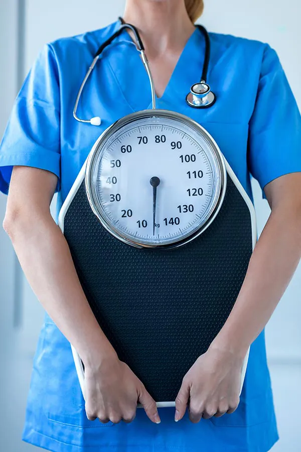A clinician holds a scale. Sign up for the weight management program with Morgan Burns, APRN in New Smyrna Beach.