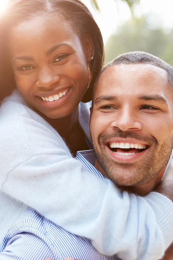 A woman riding on a man's back, both smiling due to help with erectile dysfunction from Brandi Terra, NP at Oak & Stone Wellness in San Diego.