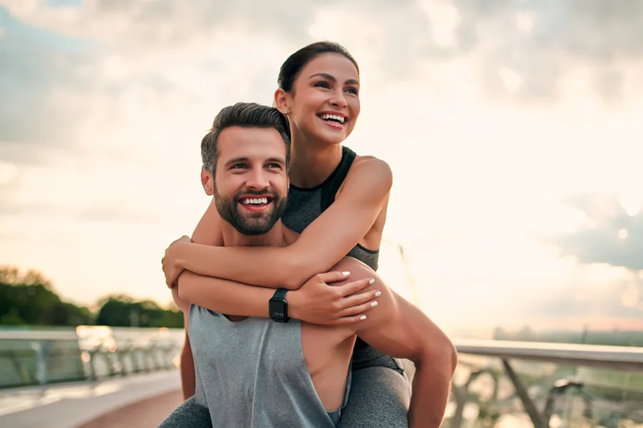 Evolve-Body-Contouring-Clinic A couple embrace on a running track at sunset. Get Evolve body contouring treatment from Brandi Terra, NP at Oak & Stone Wellness in San Diego.
