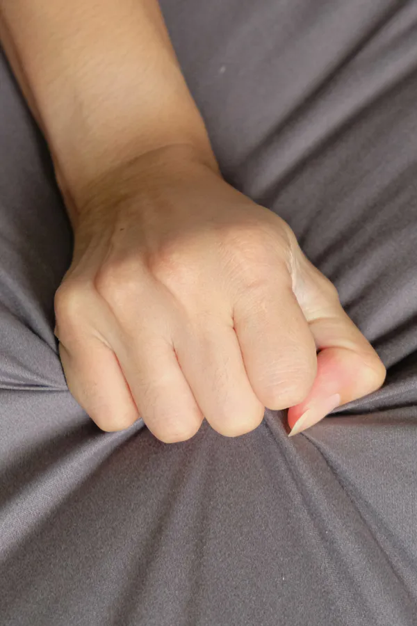 Close-up of a woman's hand grabbing a sheet, indicating sexual pleasure. Get female sexual dysfunction treatment from Brandi Terra, NP at Oak & Stone Wellness in San Diego.