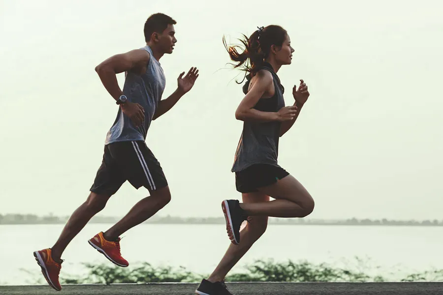 A couple in profile running along the water. Schedule GLP-1 Weight Loss Injections from Brandi Terra, NP at Oak & Stone Wellness in San Diego.