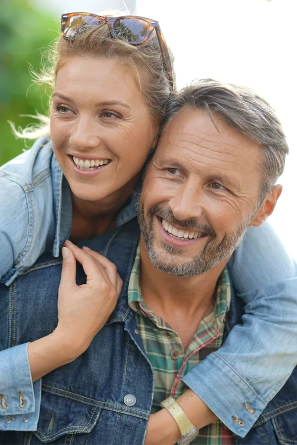 A couple in denim jackets embrace playfully outdoors. Get hypogonadism treatment from Brandi Terra, NP at Oak & Stone Wellness in San Diego.