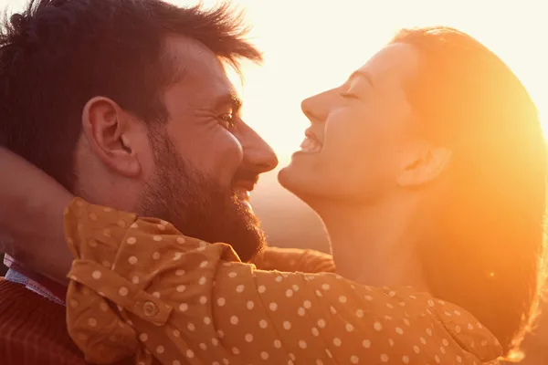 A happy couple embracing, framed by the sunset. Schedule ozone IV therapy from Brandi Terra, NP at Oak & Stone Wellness in San Diego.