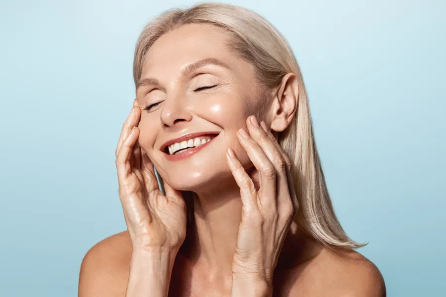 A woman with a smooth, tight jawlline smiles and holds her face. Schedule Radiofrequency Microneedling for Face and Jawline Skin Treatment from Brandi Terra, NP at Oak & Stone Wellness in San Diego.