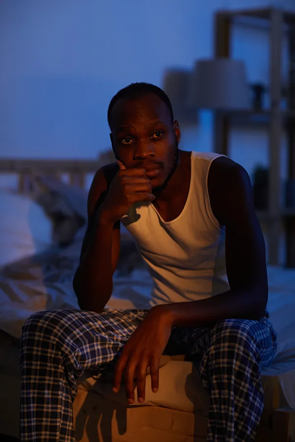 A man sits on the edge of his bed concerned that he can't sleep. Get treatment for sleep disorders from Brandi Terra, NP at Oak & Stone Wellness in San Diego.