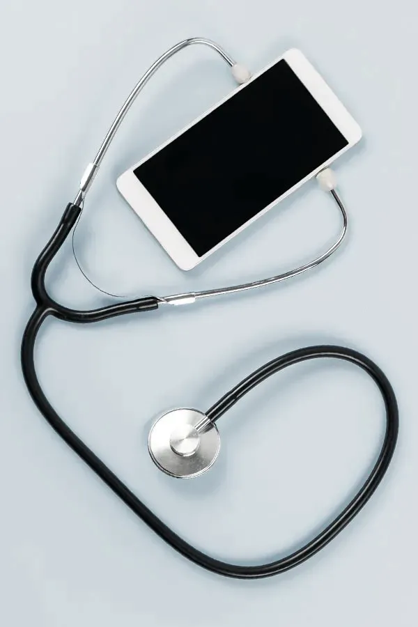A smartphone with a stethoscope attached to it, symbolizing Telemedicine treatment from Brandi Terra, NP at Oak & Stone Wellness in San Diego.