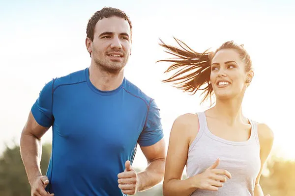 A couple happily jogging in the sunlight after receiving effective weight loss resistance care from Brandi Terra, NP at Oak & Stone Wellness in San Diego.